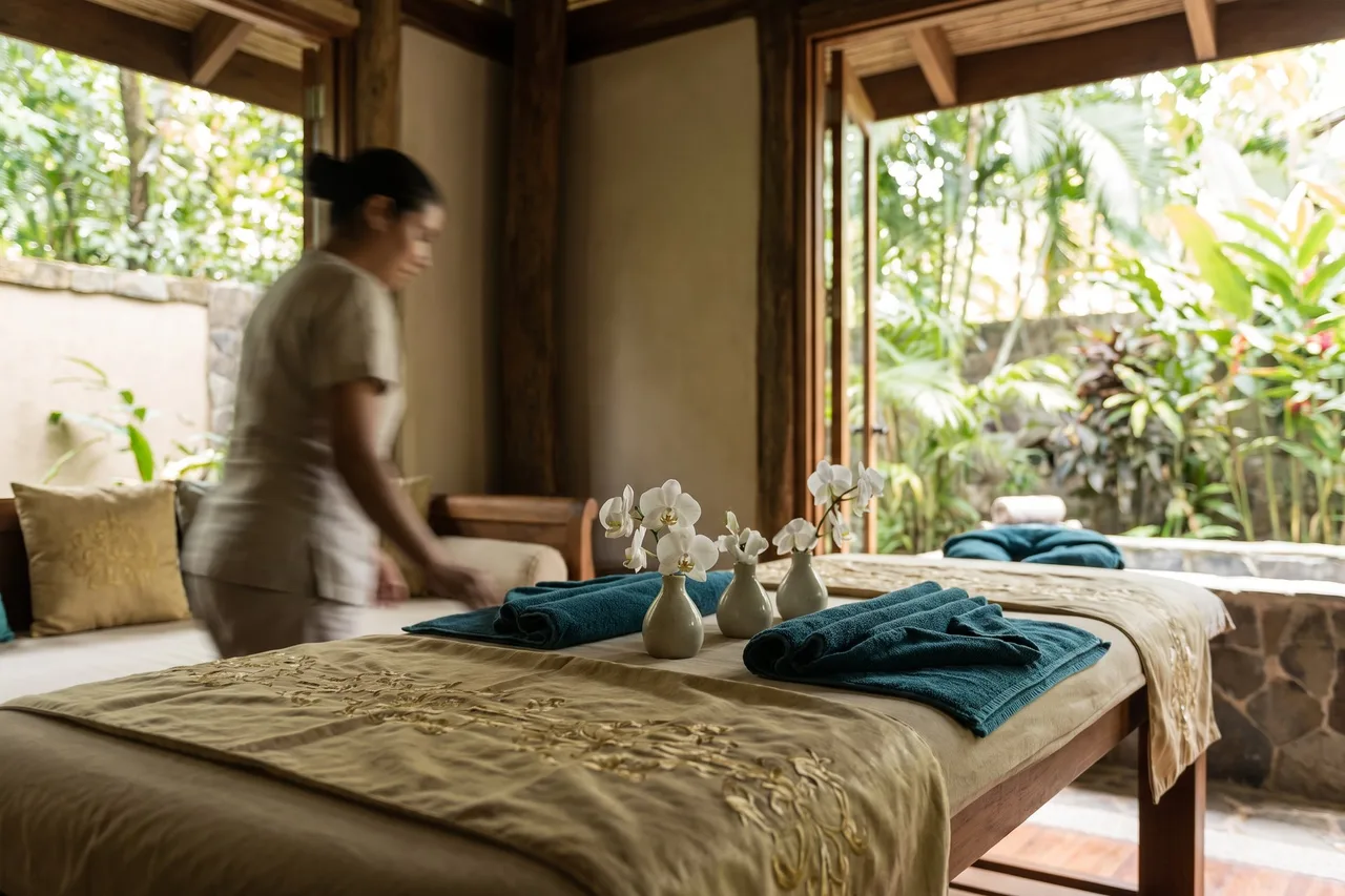 A massage table set with orchids and rolled towels in a spa pavilion